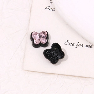 Détail macro de breloques papillon en cristal rose montrant le design avant et arrière