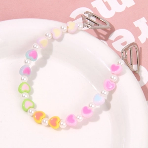 Detailed macro view of colorful macaron heart beads and white pearls on a shoe chain