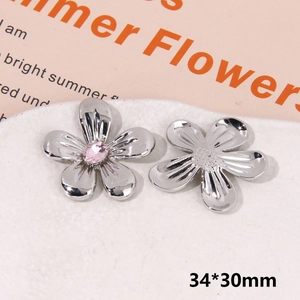 Macro detail of silver floral shoe charms with pink rhinestone and textured metal finish
