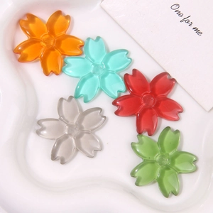 Macro shot of translucent five-petal cherry blossom resin charms in five vibrant colors