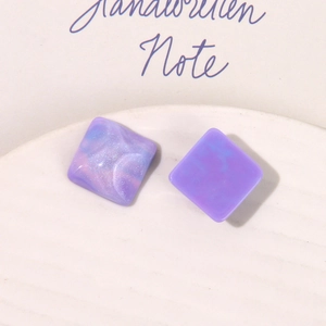 Close-up of square resin earrings featuring purple marble texture and glitter accents