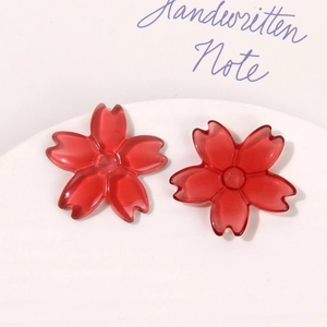 Close-up of translucent red resin cherry blossom charms for DIY jewelry and crafts