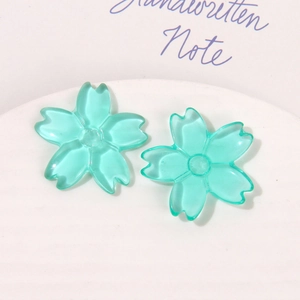 Close-up of translucent teal cherry blossom resin charms for DIY earring and jewelry crafts