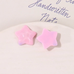 Macro shot of pink starry glitter resin star charms with blue marble effect for DIY crafts