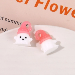 Macro shot of cute ghost resin charms with pink hats on a white ceramic plate