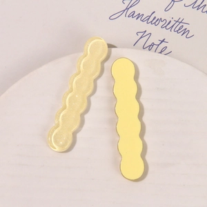 Detalle macro de pinzas para el cabello de resina con purpurina ondulada en amarillo