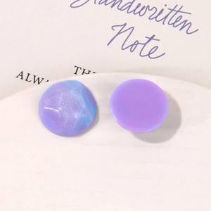 Dettaglio di ciondoli in resina viola con glitter e sfumature su piatto in ceramica