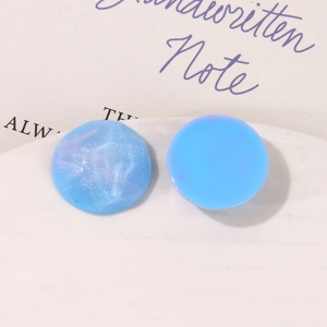 Dettaglio macro di cabochon tondi in resina azzurra con sfumature marmoree e glitterati