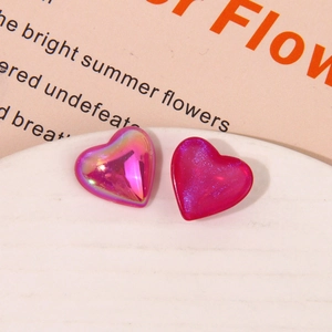 Macro view of iridescent aurora and magenta glitter resin heart charms on a white tray