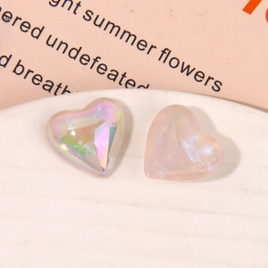 Macro view of aurora heart resin charms and glittery pink acrylic accessories for DIY crafts