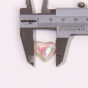 Macro view of iridescent 11mm resin heart charm being measured by a caliper