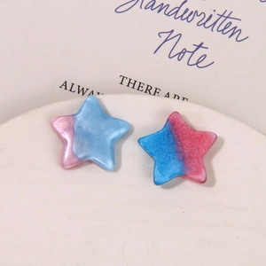 Macro shot of gradient pink and blue glittery star-shaped resin charms for DIY jewelry
