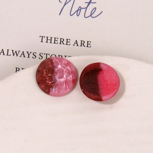Close-up of DIY resin jewelry parts with round hammer texture and smooth pink surface