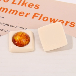 Macro detail of geometric square resin earrings with amber inserts on stone display