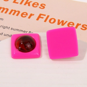 Close-up of bright pink square resin earrings with amber dome inlay and smooth finish