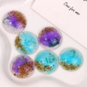 Detail view of round resin cabochons with purple and blue sea sand art effects