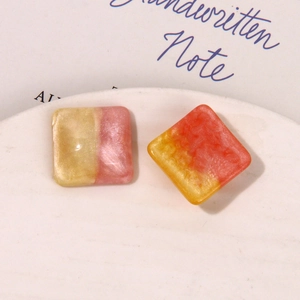 Macro shot of square resin earring charms with galaxy glitter and colorful marble texture