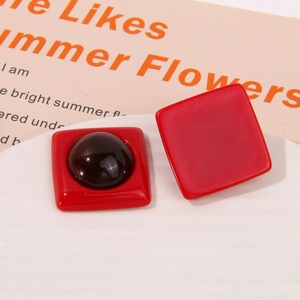 Detailed close-up of red geometric resin square stud earrings on an artistic card