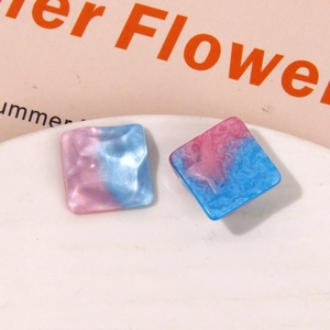 Close-up of square resin charms with pink and blue gradient glitter wave texture