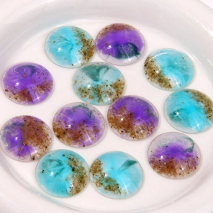 Detail of dreamlike purple and blue resin cabochons with sand-like texture on white plate