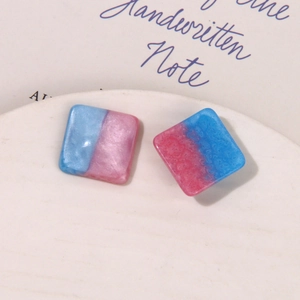 Macro shot of square resin earring charms with pink and blue starry glitter texture