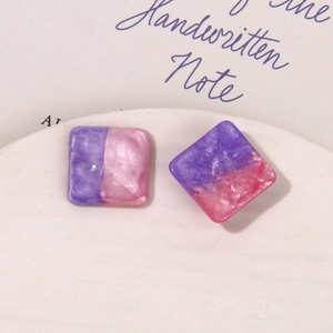 Close-up of square resin earrings with purple and pink glitter sand marble texture