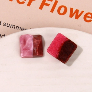 Detail of square resin jewelry charms with wave textures and glitter on ceramic plate