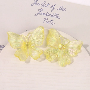 Detailed macro view of yellow iridescent acrylic butterfly charms with fine textures