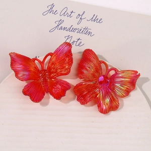 Close-up of iridescent magenta acrylic butterfly jewelry with metallic wing texture