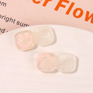 Detail of square resin accessories with soft pink smiley faces and marbled smoke texture