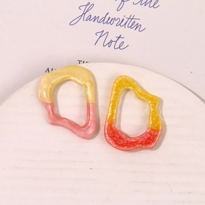 Close-up of geometric resin earrings with pearlescent gradient on a ceramic plate