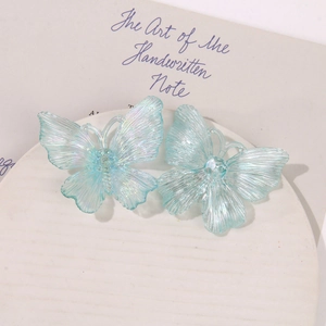 Macro view of translucent light blue iridescent acrylic butterfly charms for DIY jewelry
