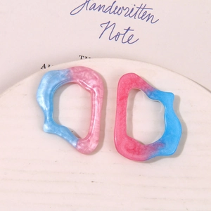 Close-up of irregular resin hollow frame pendants with pink and blue gradient marble finish