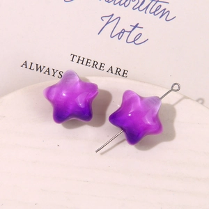 Detalle de dijes de estrellas moradas degradadas de resina en una bandeja blanca