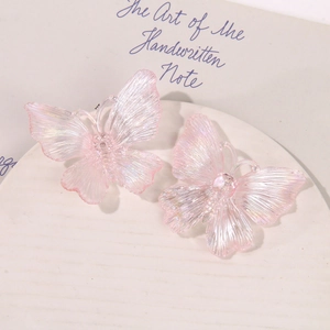 Detailed macro view of pearlescent pink acrylic butterfly jewelry accessories in soft light