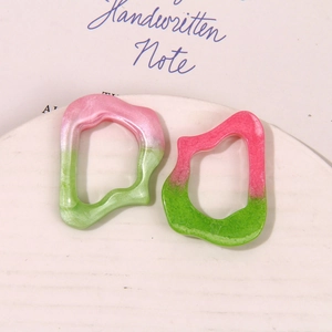 Macro detail of gradient resin earring pendants with irregular geometric hollow design
