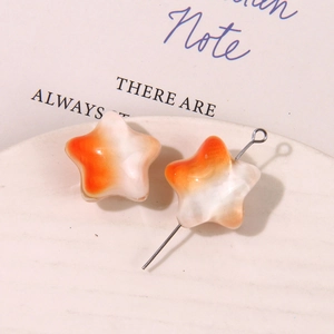 Vista de cuentas de estrella con degradado naranja sobre plato blanco para joyería