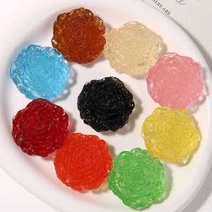Top view of nine colorful resin rose flower charms for DIY jewelry making on white plate