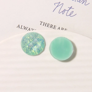 Detailed macro view of mint green resin and iridescent glitter geometric earring charms
