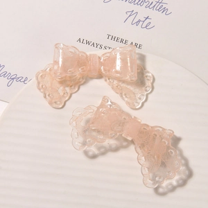 Detailansicht von zwei rosa Harz-Haarspangen mit feiner Spitzentextur auf weißem Tablett