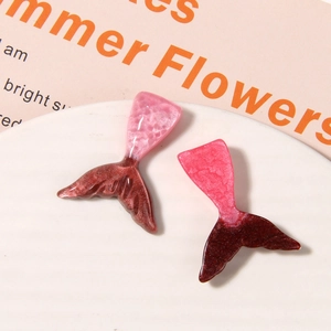 Close-up of glittery resin mermaid tail charms for DIY shoe accessories in pink and maroon