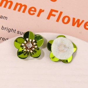 Macro shot of green sequin flower charms with rhinestone center for DIY apparel decor