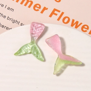 Macro shot of glittery resin mermaid tail charms with gradient pink and green scales