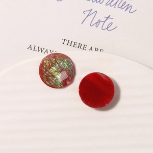 Detailed macro view of geometric red resin charms with embedded gold and green foil flakes