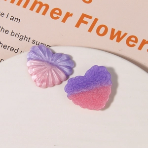 Macro shot of glittery heart-shaped resin charms with radial texture in pink and purple