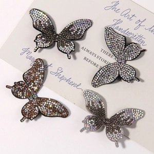 Close-up of four sparkling rhinestone butterfly charms on a white decorative card