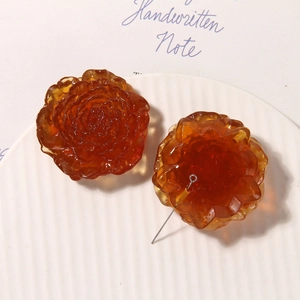 Detailed macro of amber translucent resin flower charms on a white ceramic tray