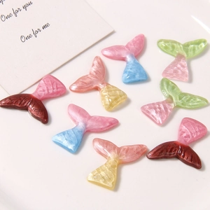 Macro detail of pearlescent mermaid tail resin charms for DIY earrings and shoe accessories