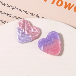 Macro view of sparkly resin heart charms with pink purple marble texture for DIY