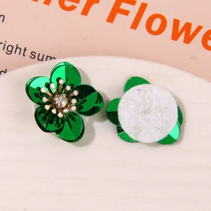 Macro detail of green metallic flower charms with faux diamond center and felt backing